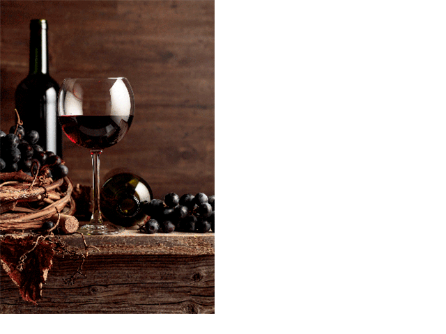 glass of red wine with two bottles and grapes on wooden background