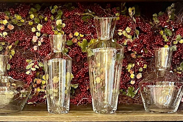 variety of glassware on wooden shelf against grapevine decoration in Vin Fromage